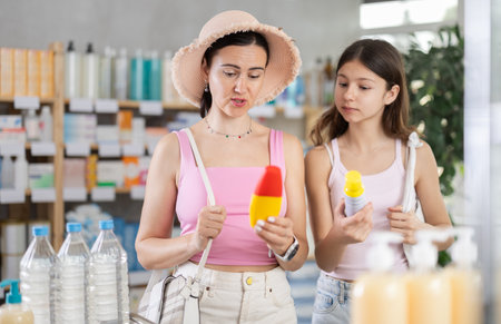 Woman buyer with teen daughter select mosquito repellent in drug storeの写真素材