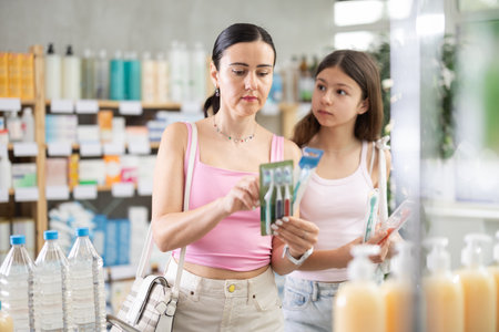 Friendly family of adult woman and young girl choosing best toothbrush at pharmacyの写真素材
