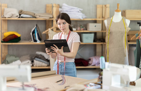 Woman dressmaker makes pattern using tablet