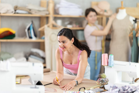 Female tailor drawing clothing outlines on paper in sewing studioの写真素材