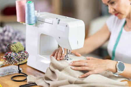 Unrecognizable woman designer sews clothes using sewing machine, close upの写真素材