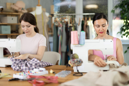 Two women tailor sews clothes in sewing machineの写真素材