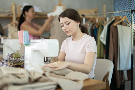 Female seamstress is sitting near sewing machine and create new dress in workshopの写真素材
