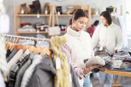 Teen girl looks at products in store and selects hat. Family shoppingの写真素材