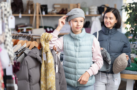 Teenage girl with her mother try on hat in storeの写真素材