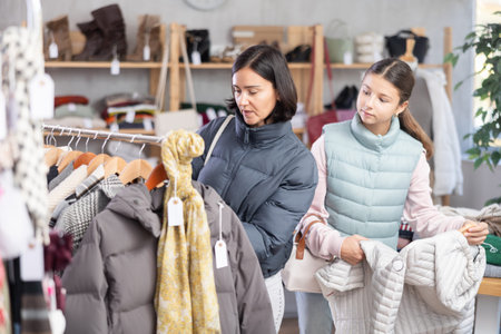 Teenage girl and her mother choose down jacket
