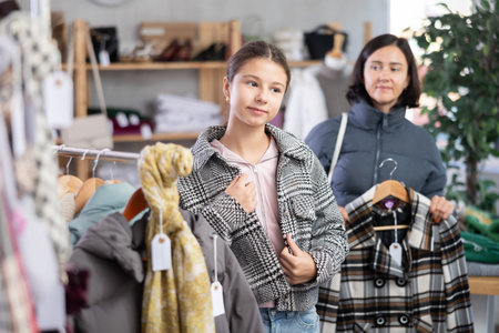 Adolescence girl try on plaid jacket during shopping with mother in clothes storeの写真素材
