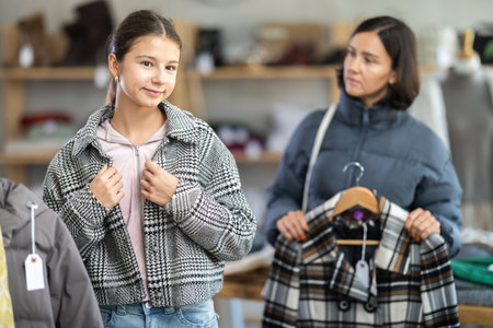 Adolescence girl try on plaid jacket during shopping with mother in clothes storeの写真素材