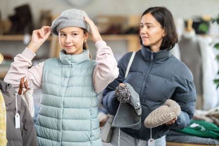 Adolescence girl try on hat during shopping with mother in clothes store, family shopping with momの写真素材