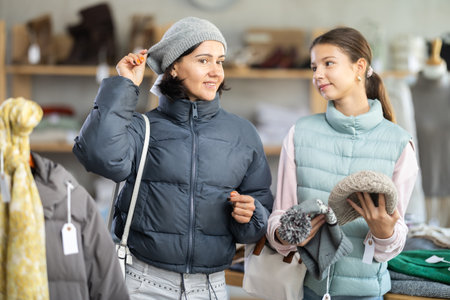 Woman with girl trying on winter hat in store, family shopping with daughter.の写真素材