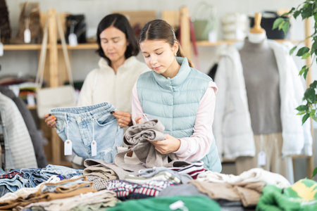 Adult woman and teenage girl choose jeans and trousersの写真素材