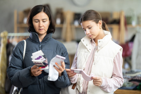 Mother and teen daughter looks at products in store and selects cotton socks.の写真素材