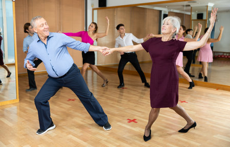 Elderly woman and man practicing jitterbug moves in dance studioの写真素材
