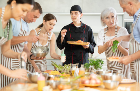 Chef in uniform teaches cooking class students how to clean and cut salmon filletの写真素材