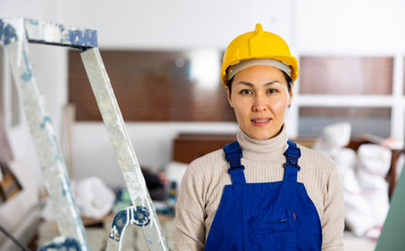 Portrait of positive woman builder standing in apartment