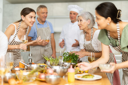 Chef and students celebrate end of cooking class with champagne and homemade salmon fillets with asparagusの写真素材