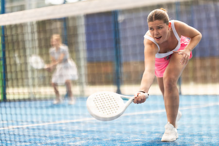 Young woman playing doubles padel tennisの写真素材