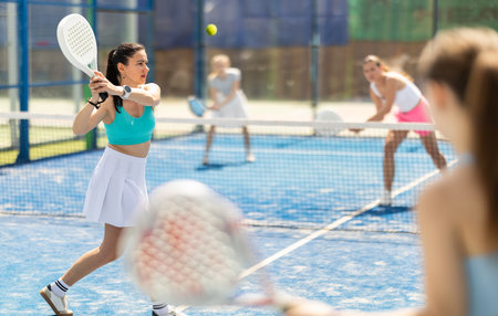 Adult woman plays paddle tennis against team of womenの写真素材