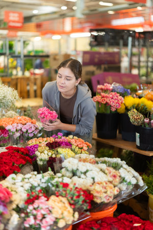 Female customer chooses a bouquet of carnations in flower shopの写真素材