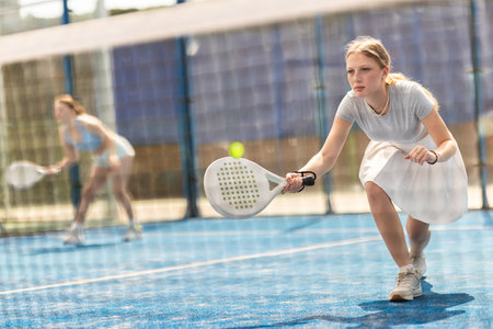 Young woman playing doubles padel tennisの写真素材