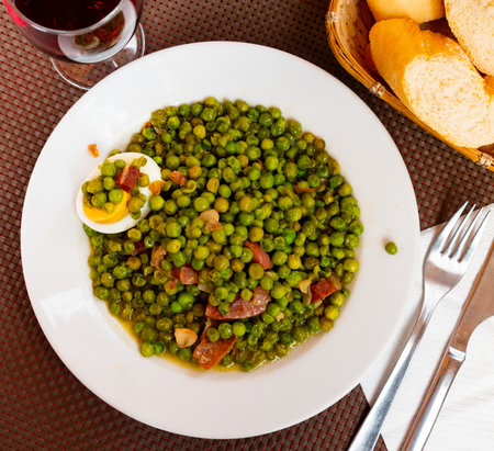 Portion of peas with ham served on table in restaurantの写真素材