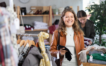 Girl carefully selects warm winter gloves in clothing storeの写真素材