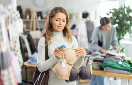 Uncertain young girl choosing bra in clothing storeの写真素材