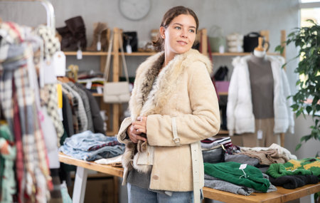 Preparing for fall and winter - girl try fur coat in clothes storeの写真素材