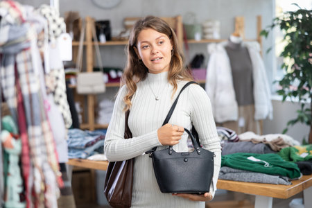 Girl chooses fashionable handbag in clothing boutiqueの写真素材