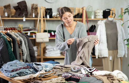 Young woman chooses sweater in clothing storeの写真素材