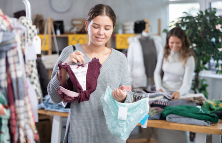 Female shopper selects panties in fashionable clothing boutique.