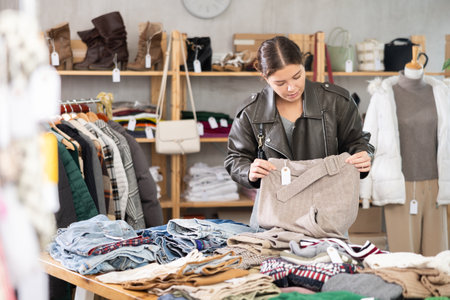 Girl chooses fashionable trousers in clothing boutiqueの写真素材