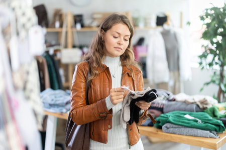 Young woman choosing gloves in clothing storeの写真素材