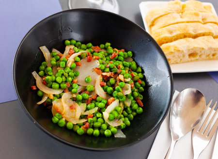 Portion of peas with ham served on table in restaurantの写真素材