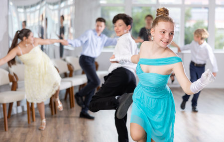 Cheerful teenage girl dancing jive with partner in choreography studio