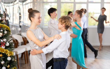 Teen boy and girl dancing waltz in couple during lesson at studio in New Year atmosphereの写真素材