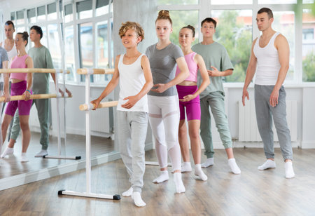 Teenage boys and girls practicing battement tendu position of ballet in dancehall