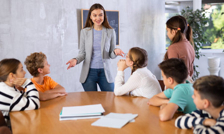 Portrait of female teacher giving lesson to children in school class