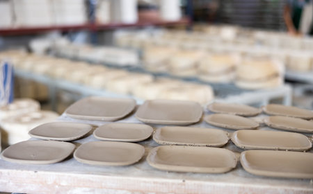 Abundance of crafted plates on shelf in ceramic workshopの写真素材