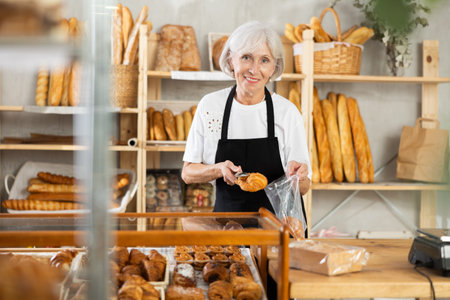 Elderly woman seller puts croissant in bag