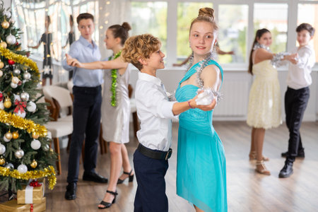 Teen boy and girl dancing waltz in couple during lesson at studio in New Year atmosphereの写真素材