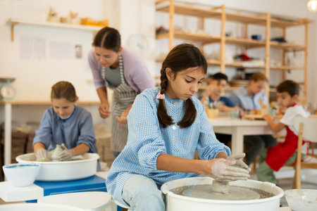 Girl working at a potters wheel with clayの写真素材