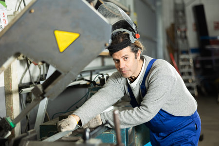 Man employee wearing safety face shield performs hazardous work in production.