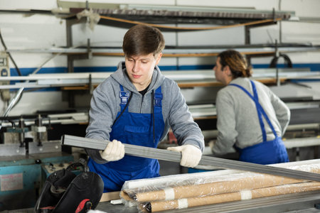 Glazer employee in blue overall works in glass processing shop