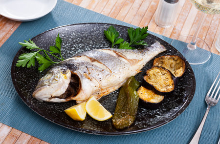 Grilled dorada with baked eggplant and pepper, fresh lemon and greens