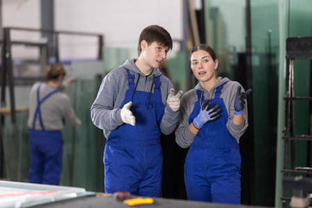 Young woman and young guy discussing work in glass factory
