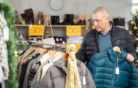 Attentive mature man choosing jacket in clothing storeの写真素材