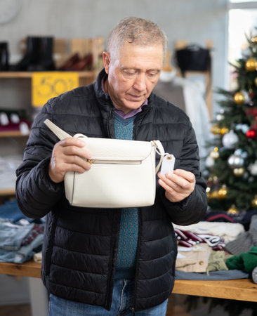 retired man chooses a handbag against the background of a Christmas treeの写真素材