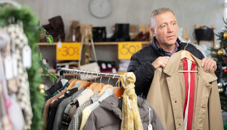 elderly man chooses a trench coat