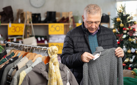 Mature man choosing a sweater at a Christmas saleの写真素材